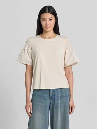 Frauenmodel trägt Regular Fit T-Shirt mit Smok-Detail von Comma aus reiner Baumwolle, ausgestellte Ärmel, Rundhalsausschnitt, kurzärmelig, beige, glatte Textur, Ganzkörperansicht von vorne.