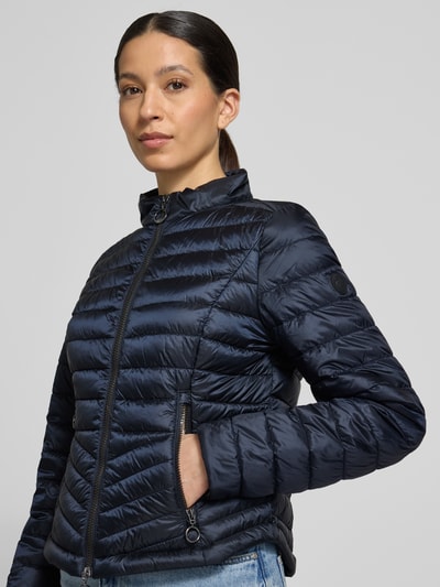 Frauenmodel trägt Steppjacke mit Stehkragen von Gil Bret in Dunkelblau, Zweiwege-Reißverschluss, Reißverschlusstaschen, Körpernahe Passform, Rückenlänge 56 cm, Schulterbreite 39 cm, Brustweite 47 cm, Ärmellänge 66 cm, Nahaufnahme Oberkörper.