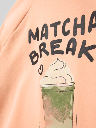 Mädchen trägt Boxy Fit T-Shirt aus Baumwoll-Mix von s.Oliver RED LABEL, Optik: Unifarben, Motiv-Print, Schriftzug, Nahaufnahme Oberkörper.