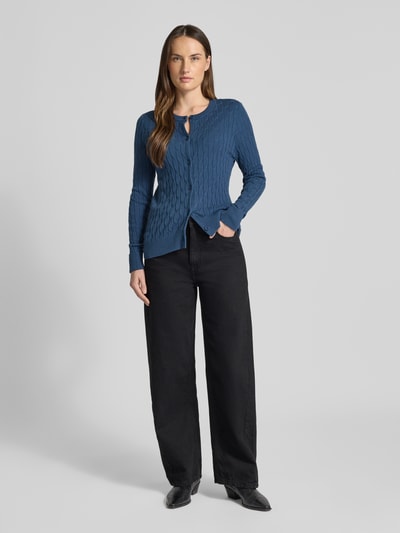 Frauenmodel trägt Regular Fit Strickjacke mit Viskose-Anteil Modell 'FANTASTIC' von Vero Moda, unifarben, Zopfmuster, Ganzkörperansicht von vorne.