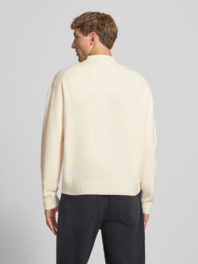 Männermodel trägt Relaxed Fit Strickpullover aus Material-Mix mit Baumwoll-Anteil von REVIEW in Beige, weiche Textur, Ganzkörperansicht Rückansicht. Rückenlänge 66 cm, Ärmellänge 61 cm, Stehkragen, elastische Abschlüsse.