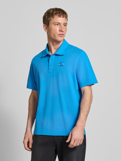 Männermodel trägt Easy Fit Poloshirt mit Polokragen von Calvin Klein Jeans in Blau, Reine Baumwolle, Label-Stitching, Ganzkörperansicht von vorne. Rückenlänge bei Größe M: 71 cm.