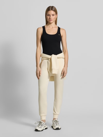 Frauenmodel trägt Slim Fit Top aus Viskose-Mix Modell 'Colette' von Guess Activewear in Schwarz, Logo-Applikation, Ganzkörperansicht von vorne.