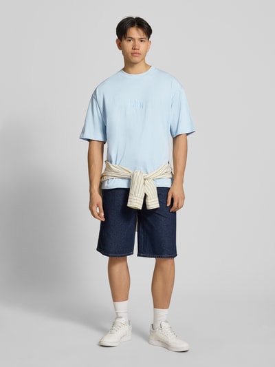 Männermodel trägt T-Shirt mit Label-Stitching und Rundhalsausschnitt von REVIEW, Relaxed-Fit aus Reine Baumwolle, hellblau, Ganzkörperansicht von vorne. Rückenlänge bei Größe M: 70 cm.
