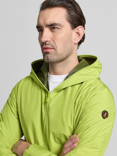 Männermodel trägt Jacke mit Zweiwegereißverschluss Modell 'Zayn' van SAVE THE DUCK in limegroen, regular fit, detailopname bovenlichaam, herenjack met ingezette zakken, capuchon, context: lengte achterkant 70 cm, schouderbreedte 47 cm, borstwijdte 57 cm, mouwlengte 68 cm