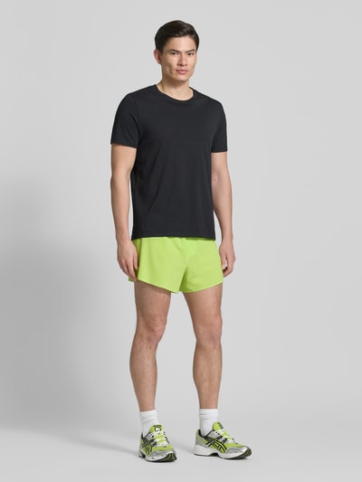 Männermodel trägt Shorts mit elastischem Bund Modell 'SENSE AERO' von Salomon in leuchtendem Grün, Material-Mix mit Stretch-Anteil, Regular-Fit, Herren Shorts, Ganzkörperansicht von vorne.