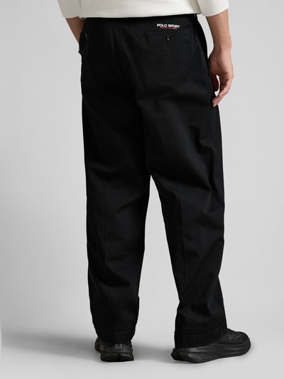 Mężczyzna nosi Regular Fit Weite Hose aus reiner Baumwolle od Polo Ralph Lauren, czarna bawełna, krój regular fit, naszywka z logo, tylne oraz boczne kieszenie, szlufki na pasek, zapięcie na guzik i kryty zamek, widok z tyłu na całe ciało.
