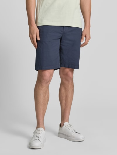 Männermodel trägt Tapered Chinoshorts aus Baumwoll-Mix Modell 'CHINO_TAPERED_DS_3S' von BOSS Orange in Dunkelblau, unifarben, Nahaufnahme Oberschenkel und Knie, Kontext: Herren Chinoshorts mit Label Patch, Gürtelschlaufen, Knopf, verdecktem Reißverschluss, Tunnelzug, elastischem Bund, seitlichen Eingrifftaschen, Gesäßtaschen.