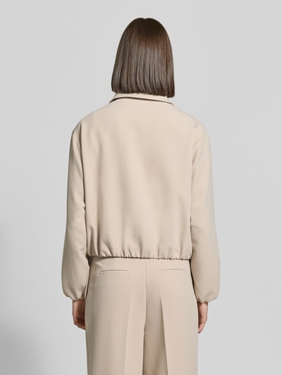 Frauenmodel trägt Regular Fit Jacke mit Viskose-Mix von MORE & MORE in Beige, glatte Struktur, elastische Abschlüsse, Ganzkörperansicht Rückansicht.