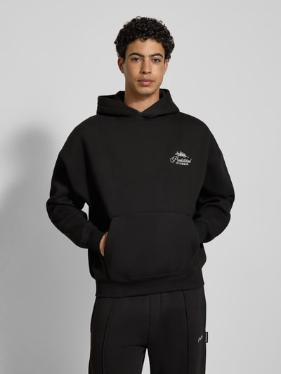 Männermodel trägt Oversized Hoodie mit Label-Stitching von PROHIBITED, schwarz, Baumwoll-Mix, Känguru-Tasche, gerippte Abschlüsse, Ganzkörperansicht von vorne.