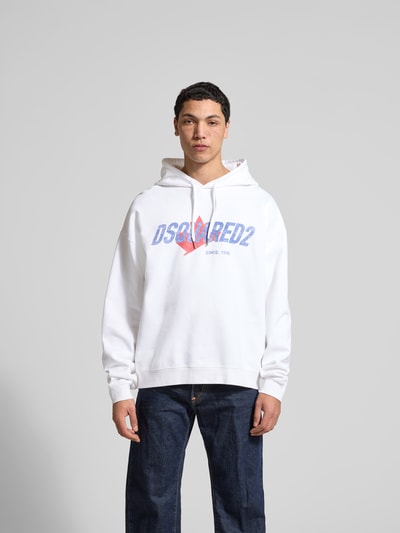 Männermodel trägt Relaxed Fit Hoodie mit Logo-Print von Dsquared2 in Weiß, reine Baumwolle, elastische Abschlüsse, Ganzkörperansicht von vorne.