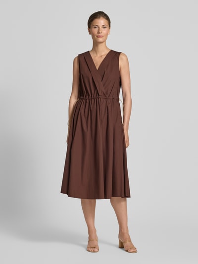 Frauenmodel trägt knielanges Cocktailkleid mit Kordelzug und Kordelstoppern von Rinascimento in Braun, reine Baumwolle, V-Ausschnitt, taillierter Schnitt, glatte Struktur, Ganzkörperansicht von vorne.