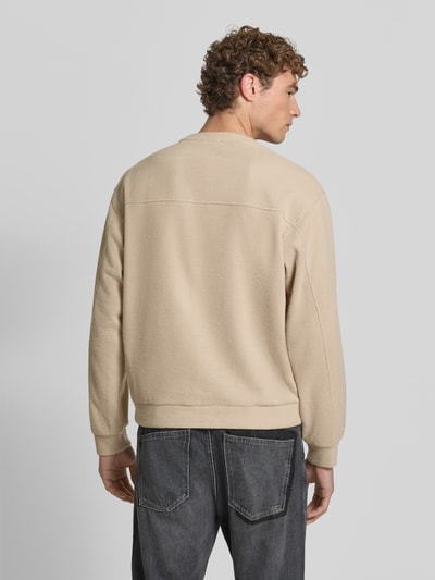 Männermodel trägt pullover met ronde hals Model 'KARIO' van DRYKORN in beige, Materiaalmix met katoen, los model, elastische boordjes, Ruglengte maat M 70 cm, Mouwlengte maat M 64 cm, Ganzkörperansicht Rückansicht.