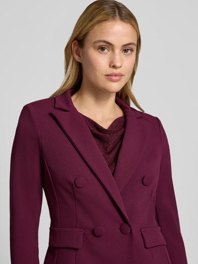 Vrouwenmodel draagt Slim Fit Blazer met Reverskraag van Rinascimento in elastische materiaalmix met dubbele knoopsluiting en klepzakken, kleur bordeaux, ruglengte maat S 53 cm, nahaufnahme bovenlichaam.