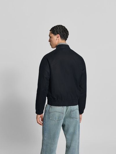 Männermodel trägt Bomberjacke aus Baumwoll-Mix von Officine Générale in Dunkelblau mit elastischen Abschlüssen, Rückenlänge 55 cm, Ganzkörperansicht Rückansicht.