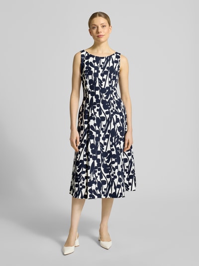 Vrouwenmodel draagt knielanges cocktailjurk met naadritssluiting van Vera Mont, elastische materiaalmix, nauwsluitende pasvorm, asymmetrische V-hals, met korte mouwen, plooien, knielengte, ruglengte maat 36: 99 cm, borstwijdte maat 36: 43 cm. Volledige lichaamsweergave van voren.