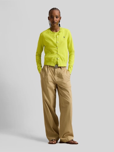 Frauenmodel trägt Regular Fit Strickjacke mit Logo-Stitching von Polo Ralph Lauren in Gelb, Rundhalsausschnitt, khakifarbene Hose, Ganzkörperansicht von vorne. Elastischer Baumwoll-Mix, durchgehende Knopfleiste, elastische Abschlüsse.