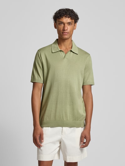 Męski model nosi Slim Fit Poloshirt aus Lyocell-Baumwoll-Mix von OLYMP Level Five, kolor zielony, kołnierzyk polo, krótki rękaw, długość tyłu w rozmiarze M: 68 cm, krój slim fit, mieszanka lyocellu i bawełny, koszulka polo dla mężczyzn, widok całej sylwetki z przodu