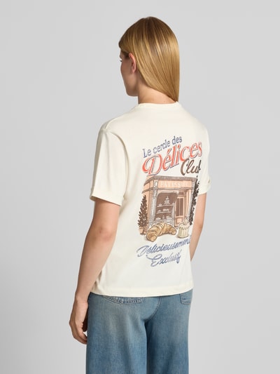 Frauenmodel trägt Relaxed Fit T-Shirt mit Ziersteinbesatz Modell 'Emotional' von GUESS in Creme mit Print, reine Baumwolle, Ganzkörperansicht Rückansicht.