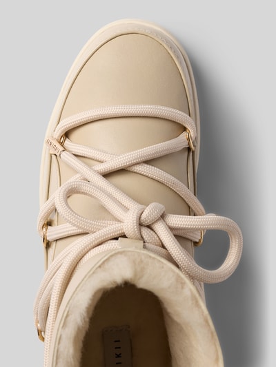 Produktfoto, Boots mit Logo-Detail von INUIKII in Beige mit runder Form, Schnürverschluss, strukturierter Sohle, beige Fütterung, Detailaufnahme, Damenmodell, Logo innen sichtbar, Schafthöhe 15 cm, Schaftweite 13 cm, Absatz 3 cm.