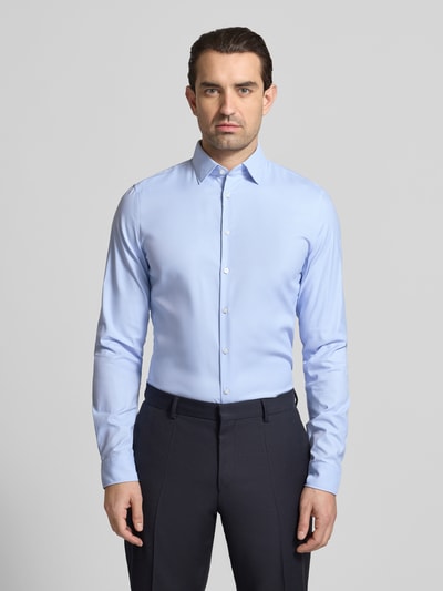 Męski model nosi Slim Fit Business-Hemd mit Kentkragen und extra langem Ärmel von Jake*s, materiał z domieszką stretchu, krój slim fit, długi rękaw, niebieski, widok całej sylwetki z przodu. Długość pleców w rozmiarze 39/40: 80 cm, szerokość w rozmiarze 39/40: 44 cm, długość rękawa w rozmiarze 39/40: 71 cm.