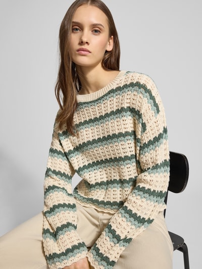 Frauenmodel trägt Regular Fit Strickpullover aus Baumwoll-Mix Modell 'ASA' von Only in Creme und Grün mit gestreiftem Lochstrickmuster, Muschelsaum an Ärmeln und Rumpf, Crew Neck, langarm, cropped Länge, Nahaufnahme Oberkörper.