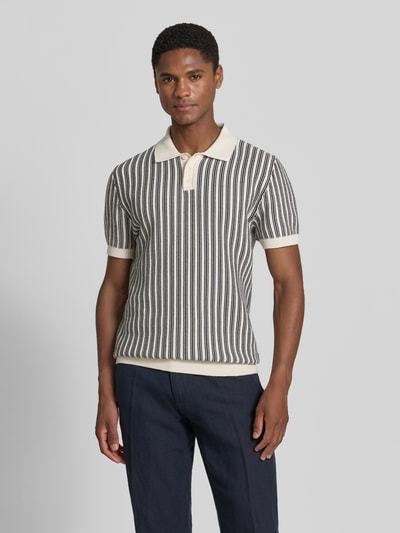 Męski model nosi Regular Fit Poloshirt in Strick-Optik od MCNEAL z bawełny, krój regular fit, imitacja dzianiny, kołnierzyk polo, krótki rękaw; długość tyłu 71 cm, długość rękawów 24 cm; widok całej sylwetki z przodu.