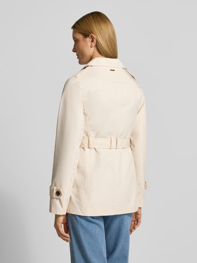 Vrouwenmodel draagt Regular Fit Trenchcoat uit katoenmix van s.Oliver RED LABEL, effen kleuren, twill, labelapplicatie, waterafstotend, achterpas, schoudertrensjes, lange mouwen, kort, tailleriem, steekzakken, eenrijige knoopsluiting, cropped lengte, achteraanzicht hele lichaam