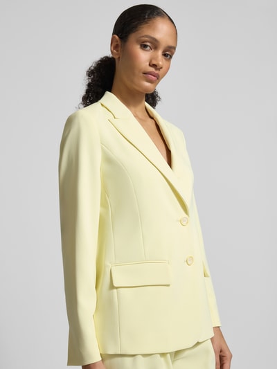 Kobiece model prezentuje Regular Fit Blazer mit Reverskragen od Marc Cain w jasnym żółtym kolorze, elastyczna mieszanka materiałów, patki kieszeni, dwurzędowe zapięcie na dwa guziki, długość pleców w rozmiarze 36: 66 cm, szerokość w rozmiarze 36: 48 cm, długość rękawa w rozmiarze 36: 62 cm, zdjęcie z przodu, ujęcie do pasa