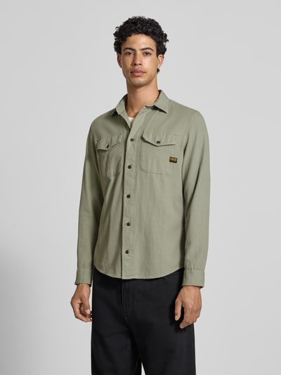Männermodel trägt Slim Fit Freizeithemd mit Label-Patch Modell 'Marine' von G-Star Raw in Olivgrün, Kentkragen, Brusttaschen, Baumwolle, Ganzkörperansicht von vorne.