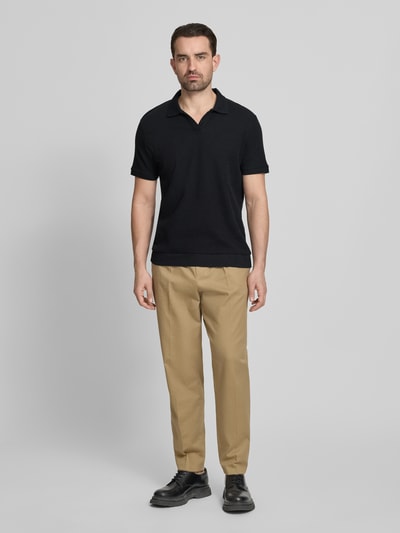 Männermodel trägt Comfort Fit Poloshirt mit V-Ausschnitt von Lindbergh in Schwarz, Reine Baumwolle, Strukturmuster, Label-Detail, Ganzkörperansicht von vorne.