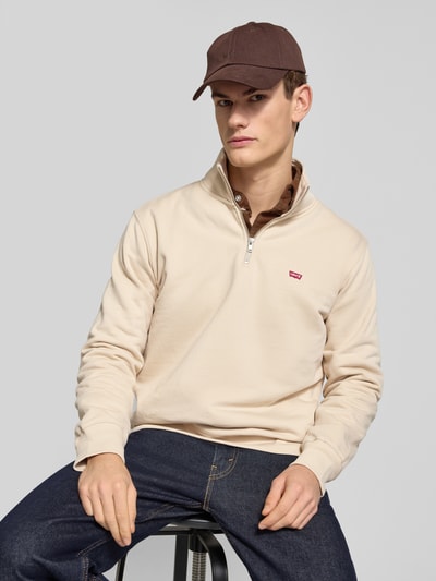 Männermodel trägt Regular Fit Troyer mit Label-Detail von Levi's®, Reine Baumwolle, Troyer-Kragen, kurzer Reißverschluss, Gerippte Abschlüsse, Rückenlänge 76 cm, Ärmellänge 65 cm, beige, glatte Textur, Ganzkörperansicht von vorne.