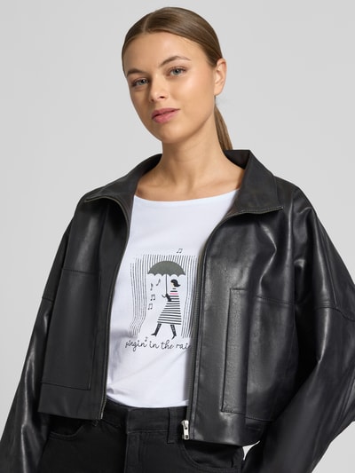Vrouwenmodel draagt Regular Fit T-shirt met strass-steentjes model 'Januar' van More & More in elastische katoenmix met modal, halve mouw, ronde hals, wit met zwarte print, detailopname bovenlichaam.