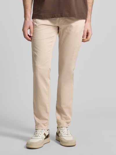Męski model nosi spodnie z wpuszczanymi kieszeniami model 'Chuck' od Brax, mieszanka bawełny i lyocellu, krój slim fit, beżowy, szerokość w rozmiarze 32/32: 43 cm, długość wewnętrzna nogawki 81 cm, zdjęcie całej sylwetki z przodu.