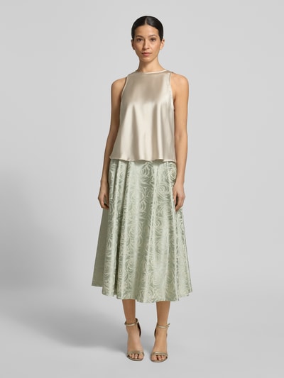 Frauenmodel trägt Midirock aus Satin mit Eingrifftaschen von Rinascimento, grün mit floralem Muster, A-Linie, Ganzkörperansicht von vorne.