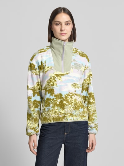 Kobiece model prezentuje Fleecepullover mit Stehkragen und Reißverschlusstaschen od Columbia w kroju regular fit, model 'Sequoia Grove™', stójka, detal z logo, kieszenie zapinane na zamek błyskawiczny, długość tyłu w rozmiarze S: 60 cm, szerokość ramion w rozmiarze S: 56 cm, szerokość klatki piersiowej w rozmiarze S: 55 cm, długość rękawów w rozmiarze S: 57 cm, wielokolorowe wzory, całość o miękkiej strukturze, Ganzkörperansicht von vorne.