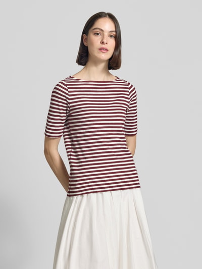 Frauenmodel trägt Slim Fit T-Shirt aus reiner Baumwolle von s.Oliver RED LABEL mit rot-weißem Streifenmuster, Jerseystruktur, U-Boot-Ausschnitt, Label Patch, Ganzkörperansicht von vorne.