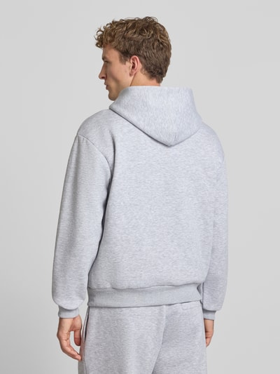 Männermodel trägt Regular Fit Hoodie aus Baumwoll-Mix von REVIEW in Hellgrau mit Kapuze und elastischen Abschlüssen, Ganzkörperansicht Rückansicht.