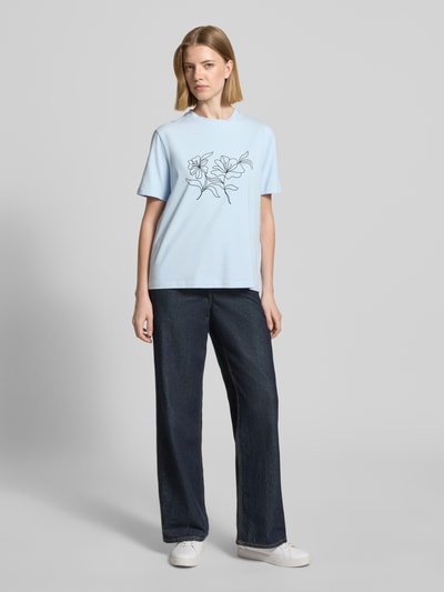 Frauenmodel trägt T-Shirt mit geripptem Rundhalsausschnitt Modell 'NORA' von Vila aus Baumwoll-Elasthan-Mix, lockerer Schnitt, Ganzkörperansicht von vorne.