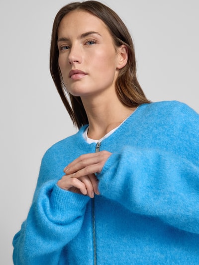 Frauenmodel trägt Oversized Strickjacke mit Reißverschluss Modell 'sasi' von Gestuz aus Alpaka-Mix mit Stretch-Anteil, Rundhalsausschnitt, gerippte Abschlüsse, leuchtend blaue Farbe, weiche Textur, Nahaufnahme Oberkörper.