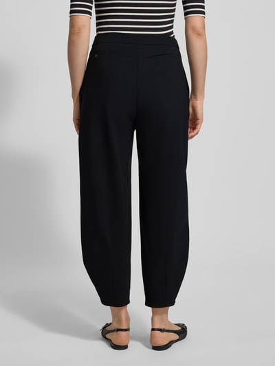 Vrouwenmodel draagt stoffen broek in zwart, los model, verkorte pasvorm met steekzakken, model 'ODINE' van Raffaello Rossi, achteraanzicht.