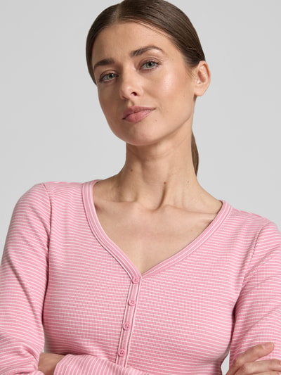 Kobiece modelka nosi Regular Fit Langarmshirt mit Henley-Ausschnitt von Tom Tailor Denim, efekt: jednolity kolor, mieszanka bawełny, różowy, dekolt henley, długi rękaw, bluzka z długim rękawem, krój regular fit, materiał miękki, z przodu guziki, Nahaufnahme górnej części ciała
