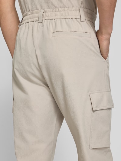Männermodel trägt Relaxed Fit Cargohose mit Gürtelschlaufen Modell 'SRACKY' von BOSS Orange, unifarben, Detailaufnahme Rückansicht.