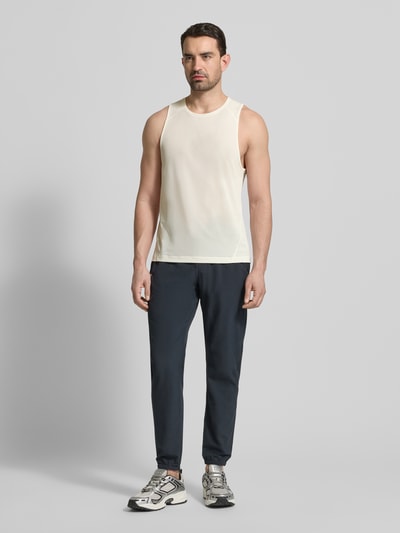 Männermodel trägt Tanktop mit Rundhalsausschnitt und Logo von Salomon in Beige, Regular Fit, glatte Textur, Ganzkörperansicht von vorne.