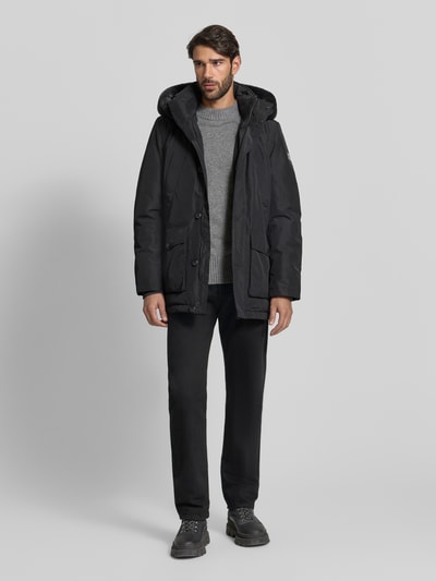 Männermodel trägt schwarze Jacke mit Sorona® Aura Filling von NAUTGÅRD, Regular-Fit, mit Kapuze und Stehkragen, Ganzkörperansicht von vorne.