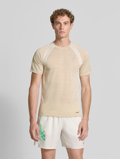 Męski model nosi Regular Fit T-Shirt mit Logo-Print Model 'Road' von ASICS TIGER, półprzezroczysty materiał, okrągły dekolt, Długość tyłu w rozmiarze M: 69 cm, całość w jasnych beżowych i białych odcieniach, Ganzkörperansicht von vorne.
