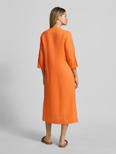 Frauenmodel trägt Tunikakleid aus Leinen mit 3/4-Arm von Emily Van den Bergh in Orange, loose Fit, mittellang, strukturierte Oberfläche, Ganzkörperansicht Rückansicht.