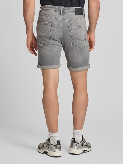 Männermodel trägt Regular Fit Jeansshorts mit Umschlag Modell 'RICK' von Jack & Jones aus Baumwoll-Elasthan-Mix, grauer Stoff mit Eingrifftaschen, Bundweite 42 cm, Innenbeinlänge 21 cm, Ganzkörperansicht Rückansicht.