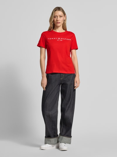 Frauenmodel trägt Regular Fit T-Shirt aus reiner Baumwolle von Tommy Hilfiger in Optik: Unifarben, Logo-Detail, Label-Schriftzug, Rundhals, Kurzarm, Materialverarbeitung: Jersey, Ganzkörperansicht von vorne.