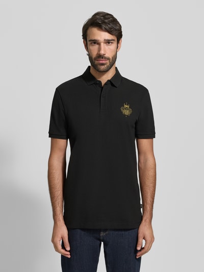 Männermodel trägt Regular Fit Poloshirt aus reiner Baumwolle Modell 'QIANG' von BOSS, Optik: Unifarben, Motiv-Label-Print, Ganzkörperansicht von vorne.